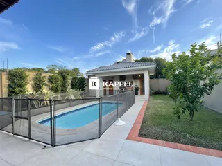 Foto de uma piscina externa cercada por grade de vidro em uma propriedade.