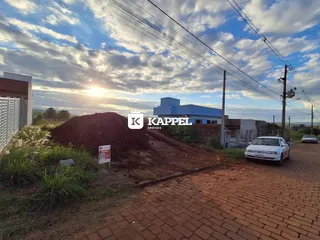 Vista externa de uma propriedade com terra exposta e um veículo estacionado.