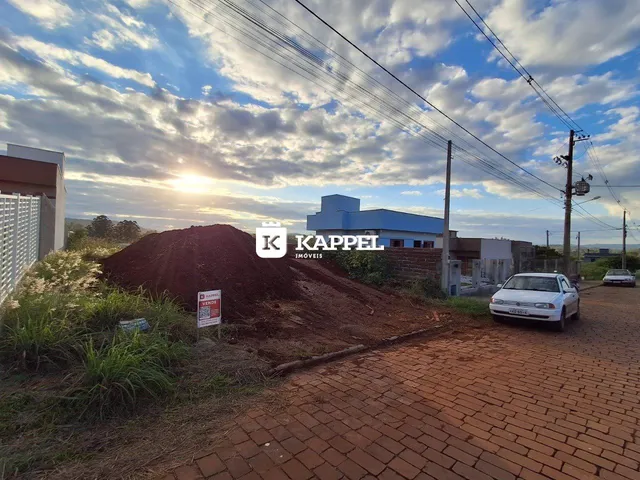 Vista externa de uma propriedade com terra exposta e um veículo estacionado.