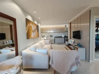 Sala de estar moderna com sofá branco e decoração clara.