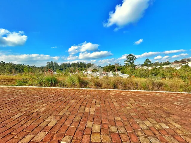 Vista da propriedade com um pátio de tijolos e vegetação ao fundo.