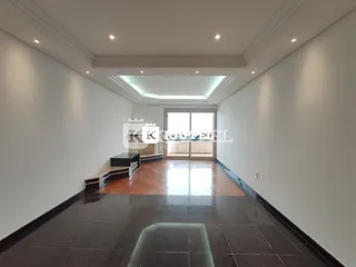 Sala ampla com piso escuro e iluminação clara no ambiente residencial.