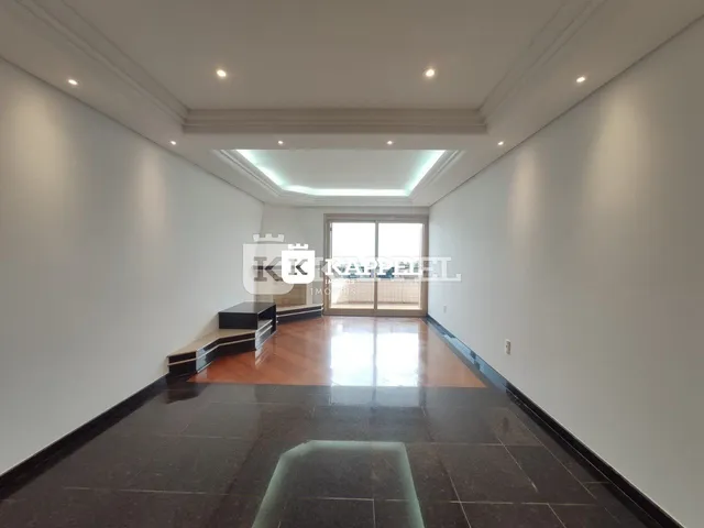 Sala ampla com piso escuro e iluminação clara no ambiente residencial.
