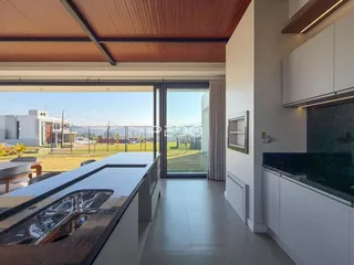 Vista da cozinha moderna com ilha e portas de vidro para o jardim.