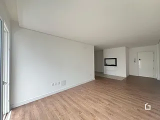 Vista interna de um ambiente com piso de madeira clara e paredes brancas.