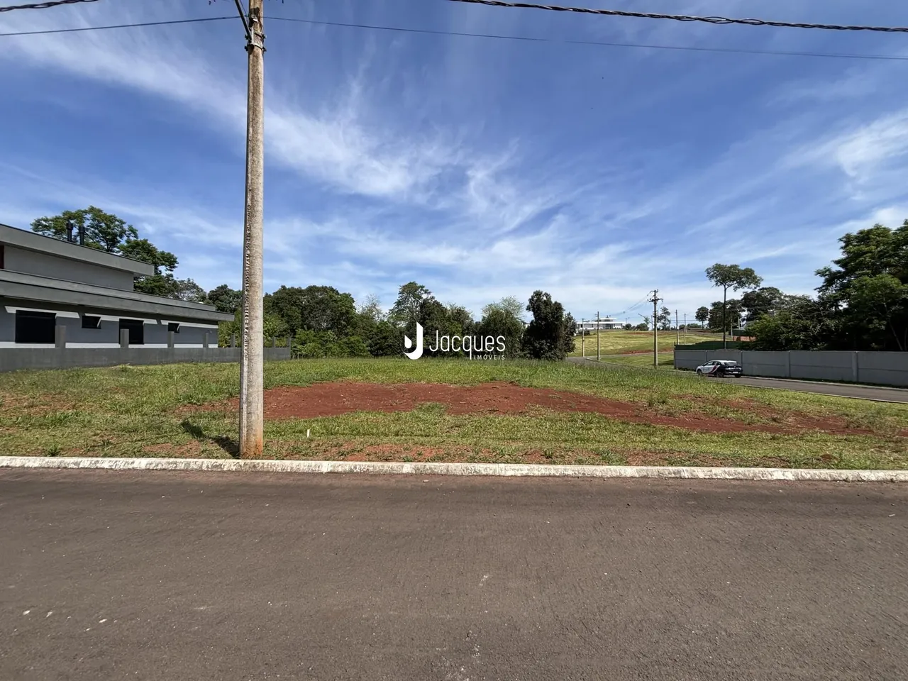 Vista externa de uma propriedade com área gramada e construção ao fundo.