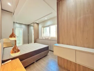 Quarto espaçoso com cabeceira de madeira e armário embutido.
