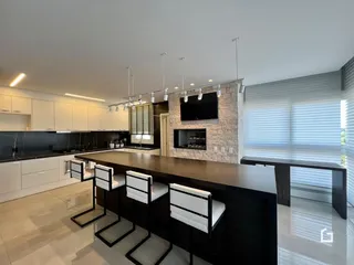 Uma cozinha moderna com ilha e armários brancos em um ambiente de sala de jantar.
