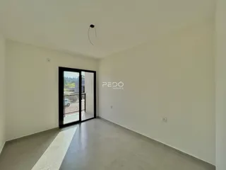 Vista interna de um ambiente com piso claro e porta de vidro.