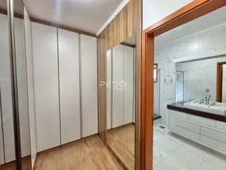 Hall de entrada com armários brancos e piso de madeira.