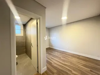 Hall de entrada com piso de madeira e acesso a um banheiro.