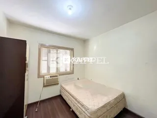 Quarto com cama e janela com persianas no imóvel.