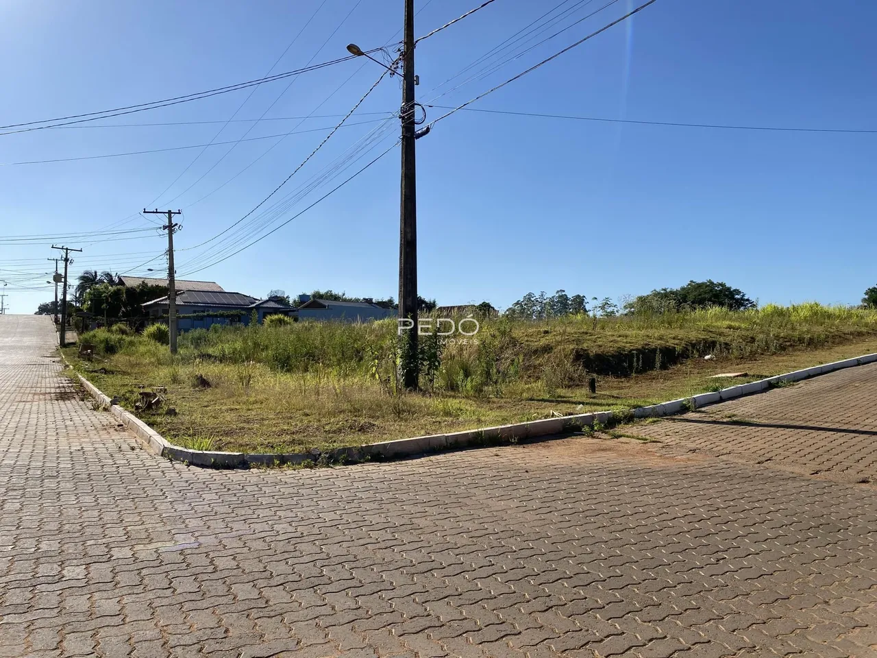 Vista externa da propriedade com área gramada e rua pavimentada.