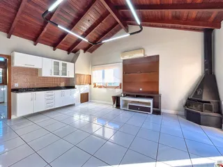 Interior de uma sala de estar com cozinha em um imóvel no Brasil.