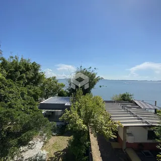 Vista da propriedade com vegetação e corpo d'água ao fundo.