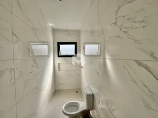 Hall de banheiro com revestimento em mármore nas paredes.