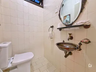Banheiro com paredes de azulejo claro e vaso sanitário branco.