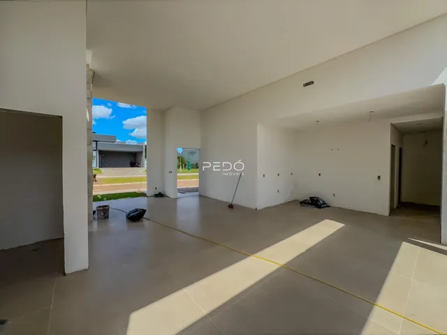 Interior de uma sala ampla com piso de cerâmica e parede branca.