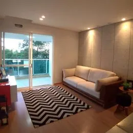 Sala de estar com sofá e portas de vidro que dão acesso a uma área externa.