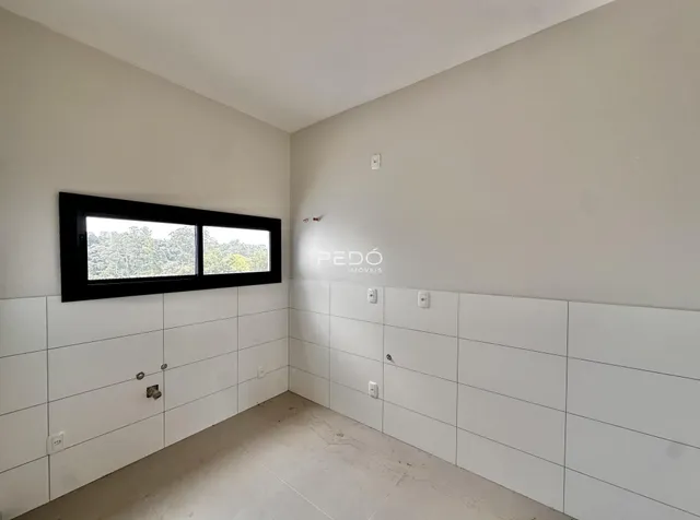 Uma parede interna com janela e revestimento branco.