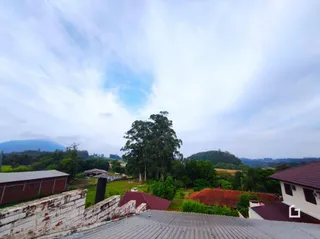 Fachada de uma propriedade em Lajeado, Brasil, cercada por vegetação e colinas.
