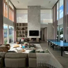 Sala de estar moderna com grandes janelas e paredes claras.