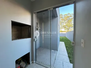Vista de uma porta de vidro que leva a um pátio externo com gramado.