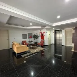 Sala de estar com piso escuro e teto branco.