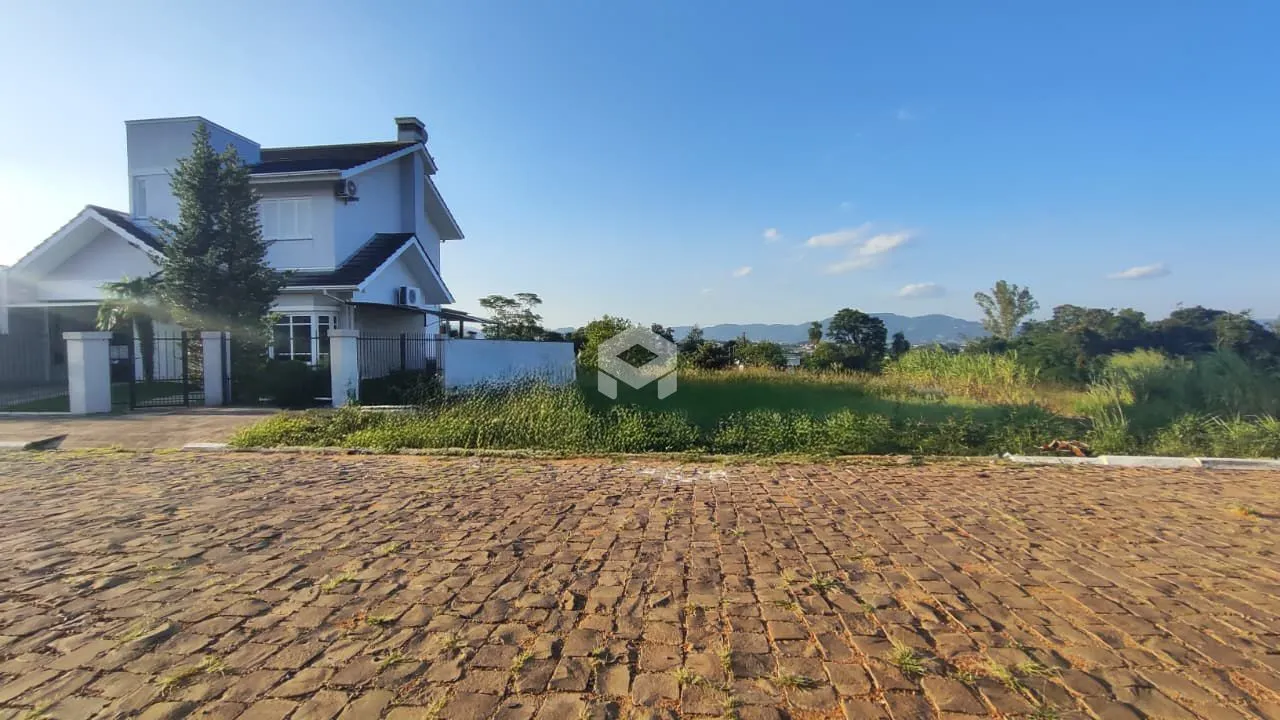 Fachada de uma casa branca em Lajeado, Brasil, com jardim e área pavimentada.