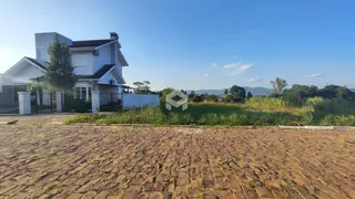 Fachada de uma casa branca em Lajeado, Brasil, com jardim e área pavimentada.