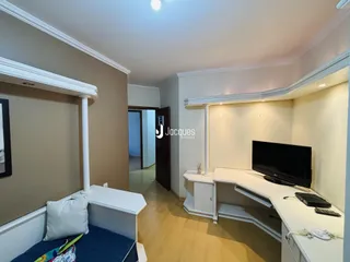 A sala de estar apresenta paredes claras e piso de madeira.