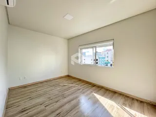 Ambiente interno de um cômodo com piso de madeira clara e paredes brancas.