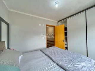 Quarto com cama de casal e paredes brancas.