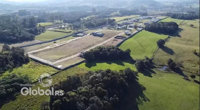 Vista aérea de uma propriedade rural com campos verdes e vegetação.