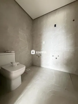 Banheiro com piso de pedra clara e vaso sanitário branco.
