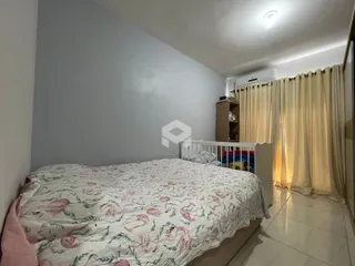 Quarto com cama e cortinas brancas em um imóvel.