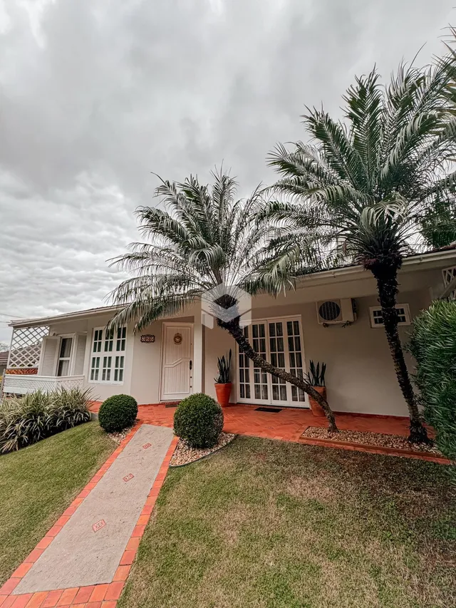 Fachada de uma casa em Lajeado, Brasil com jardim e palmeiras.