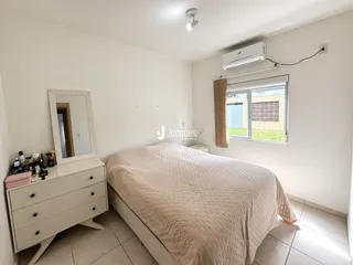 Quarto com cama e janela em ambiente claro.