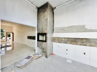Interior de uma área em construção com paredes e coluna de concreto expostas.