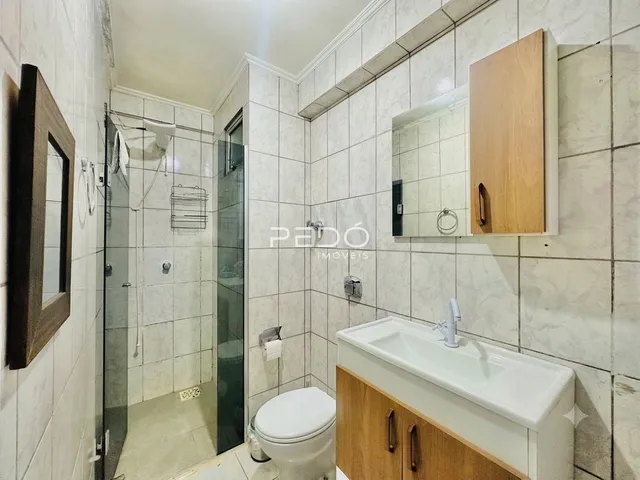 Banheiro com revestimento cerâmico e box de vidro.