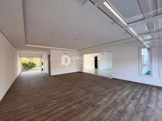 Uma sala de estar ampla com piso de madeira e teto branco.