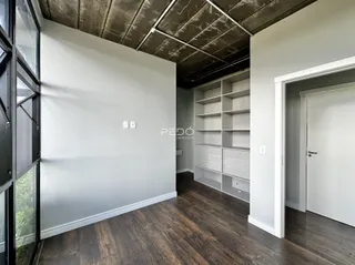 Ambiente interno com piso de madeira e estante branca em um imóvel.
