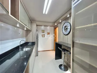Vista da cozinha com armários brancos e bancadas escuras.