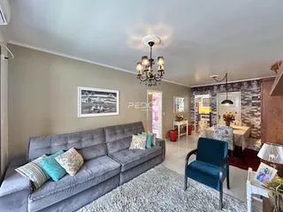 Sala de estar com sofá cinza e decoração de parede em Lajeado.