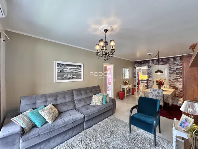 Sala de estar com sofá cinza e decoração de parede em Lajeado.