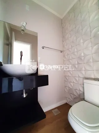 Foto de um banheiro com bancada escura e revestimento de parede branco.