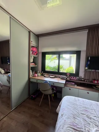 Um quarto com cama e estantes em madeira é visível na imagem.
