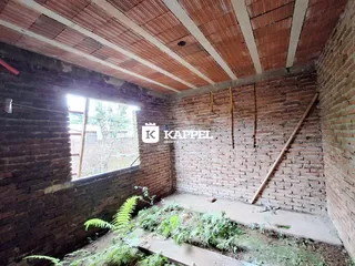 Foto de um interior com paredes de tijolo aparente e piso de terra.
