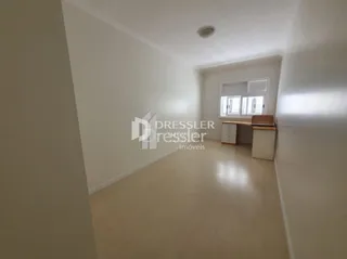 Vista interna de um corredor claro com paredes brancas e piso claro.