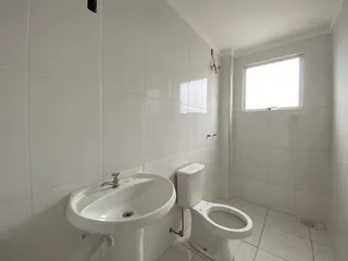 Banheiro com pia e vaso sanitário brancos e revestimento de azulejos brancos.